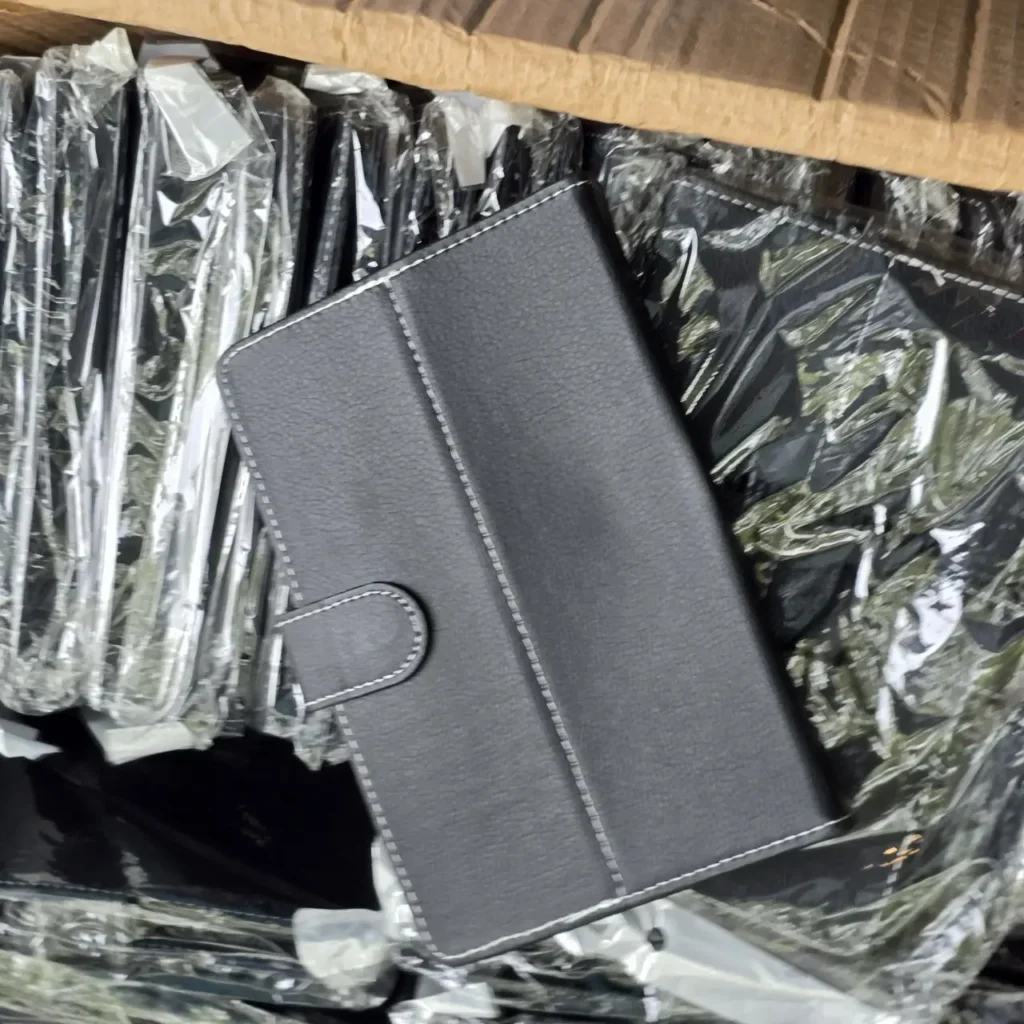 Funda de tablet gris oscuro de piel sintética con costuras blancas, en un lote de fundas empaquetadas. by Remates Narvaja