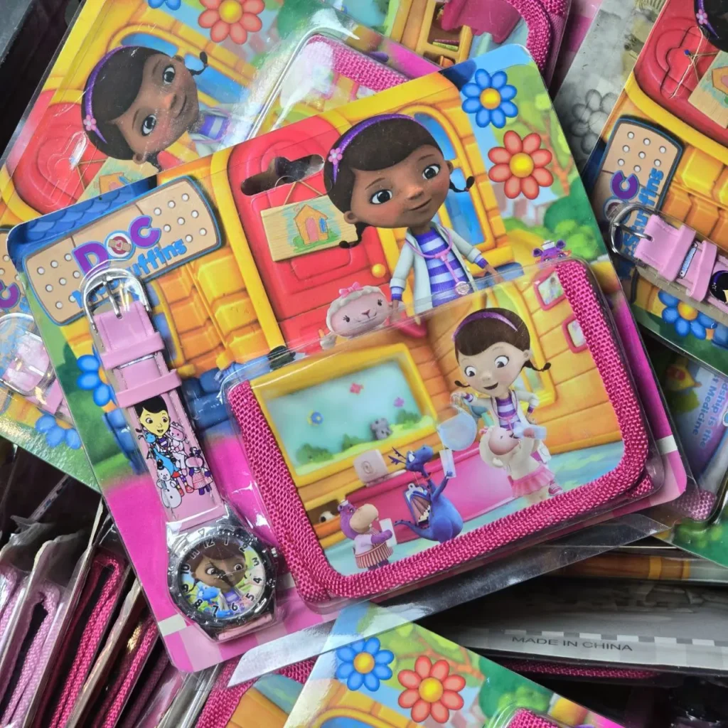 Productos de Doc McStuffins, incluyendo un reloj infantil rosa y una cartera, en empaques coloridos. by Remates Narvaja