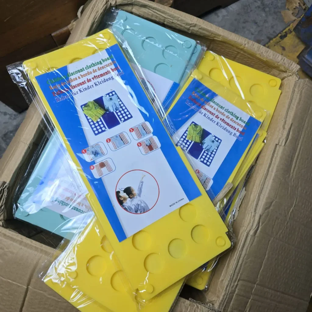 Caja con tablas plegables de ropa infantil de plástico amarillo y azul. by Remates Narvaja