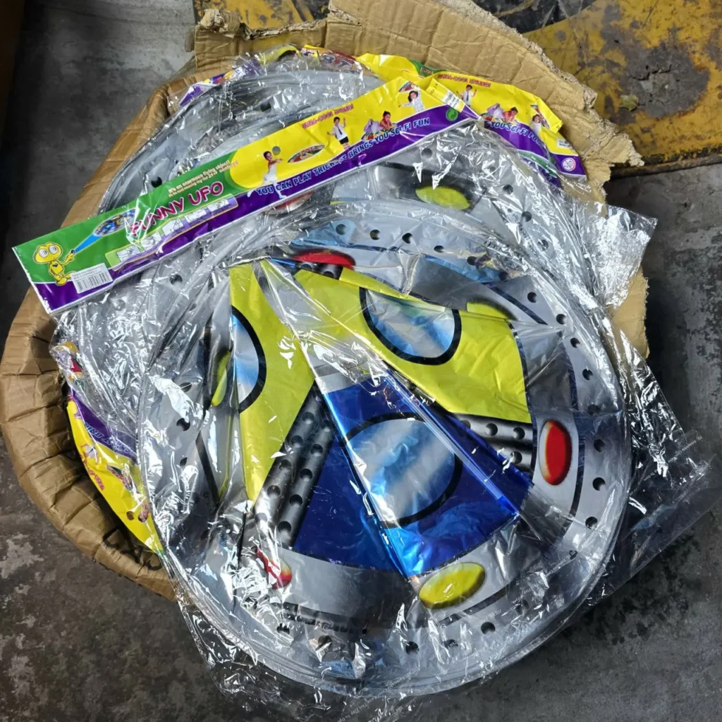 Caja de cartón llena de juguetes platillo volador Funny UFO, empaquetados individualmente con diseños de naves espaciales metálicas. by Remates Narvaja