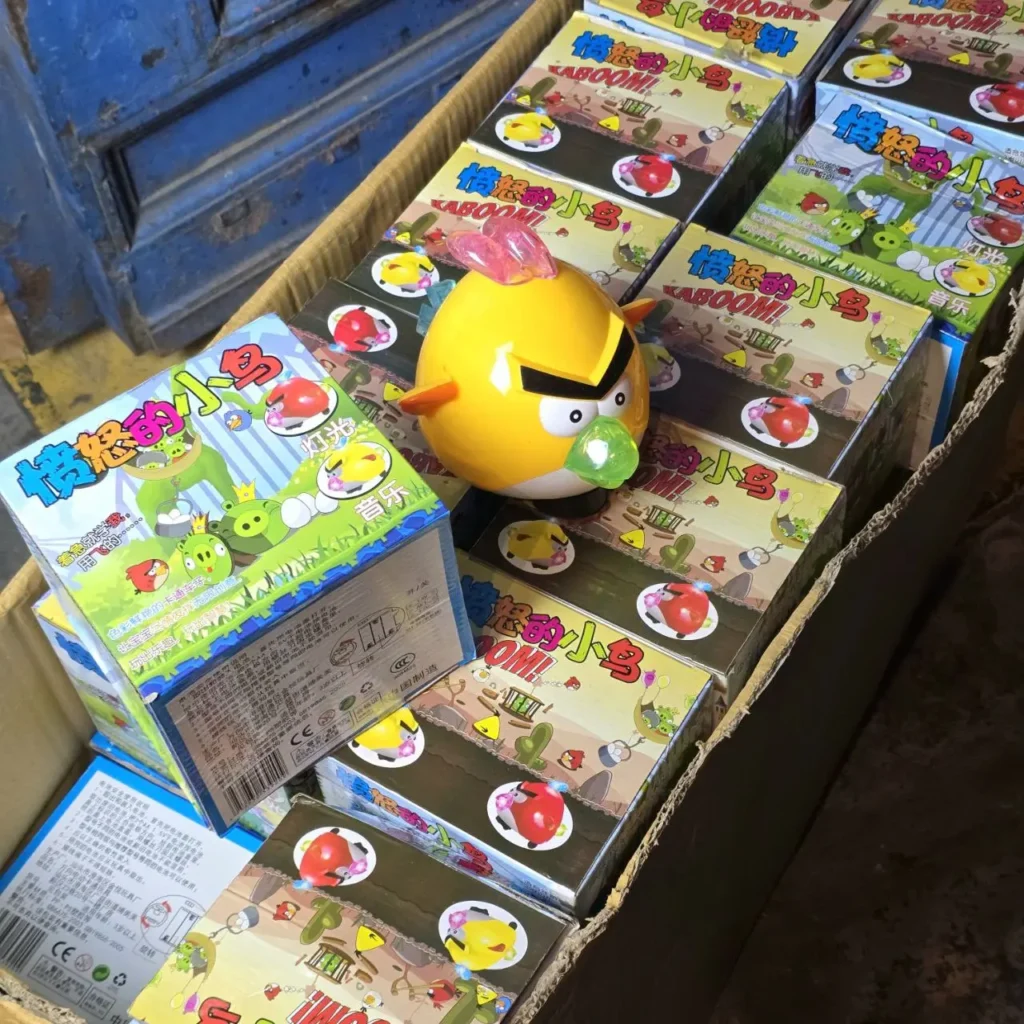 Juguete de Angry Birds amarillo sobre cajas apiladas de juegos y mercancía de Angry Birds en una caja de cartón. by Remates Narvaja