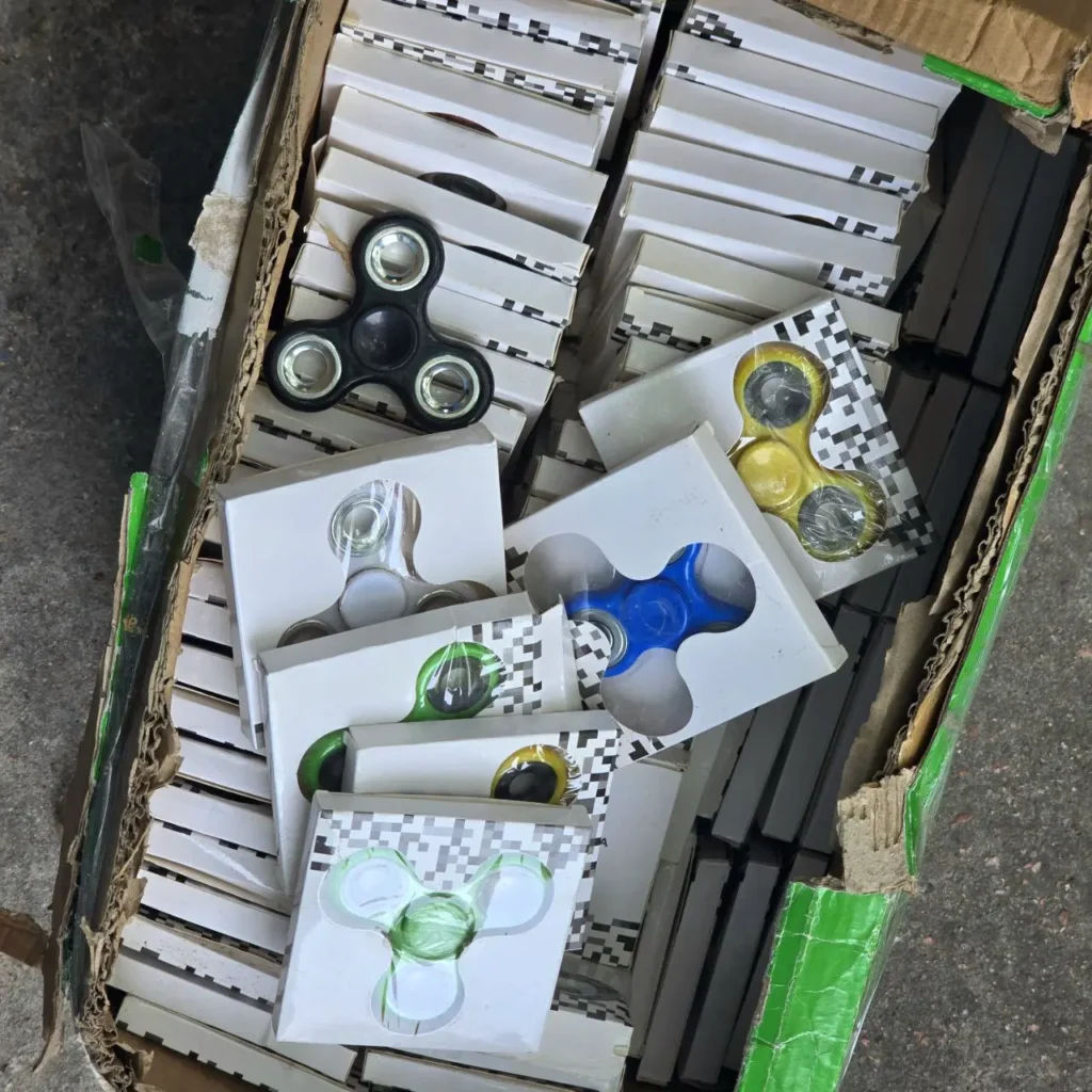 Caja con un surtido de fidget spinners de colores en sus empaques individuales. by Remates Narvaja