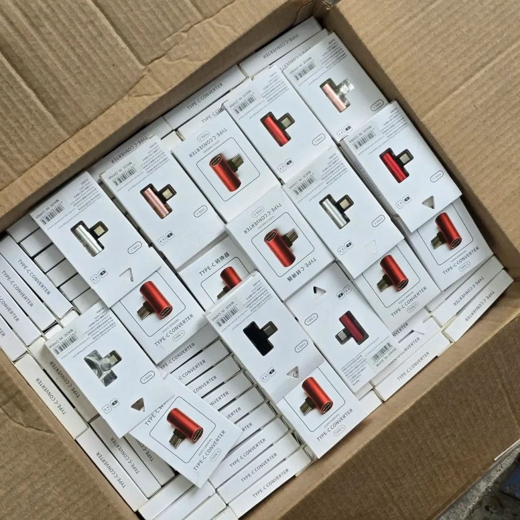 Caja llena de convertidores USB-C para audio y carga, en varios colores. by Remates Narvaja