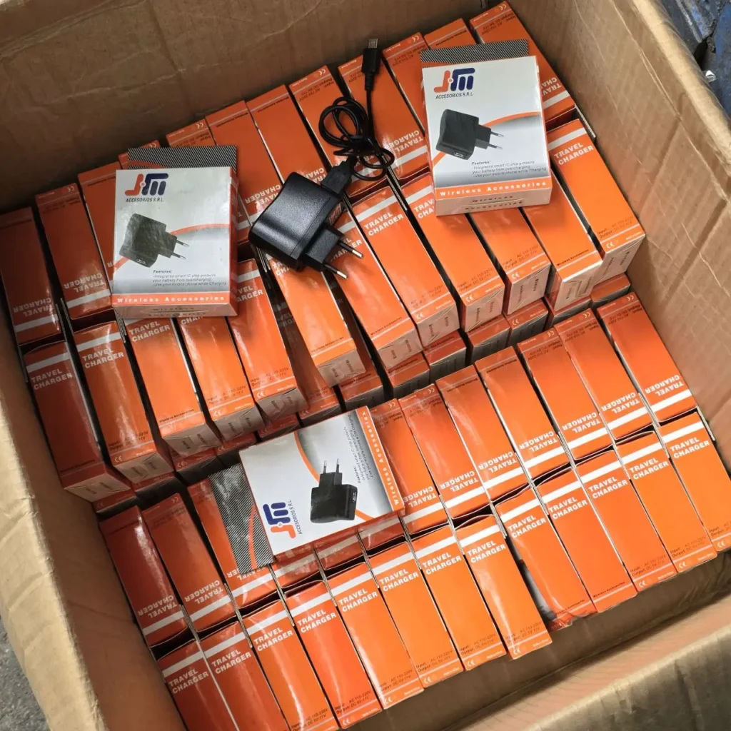 Caja de cartón llena de cargadores de viaje en cajas individuales naranjas. by Remates Narvaja