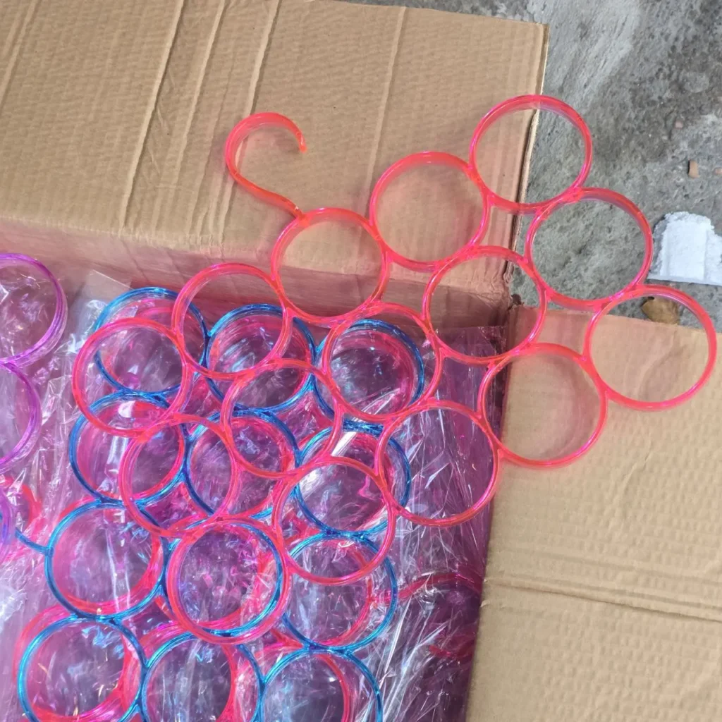 Colgador organizador de bufandas y corbatas de plástico con anillos múltiples, en rosa y azul, en una caja. by Remates Narvaja