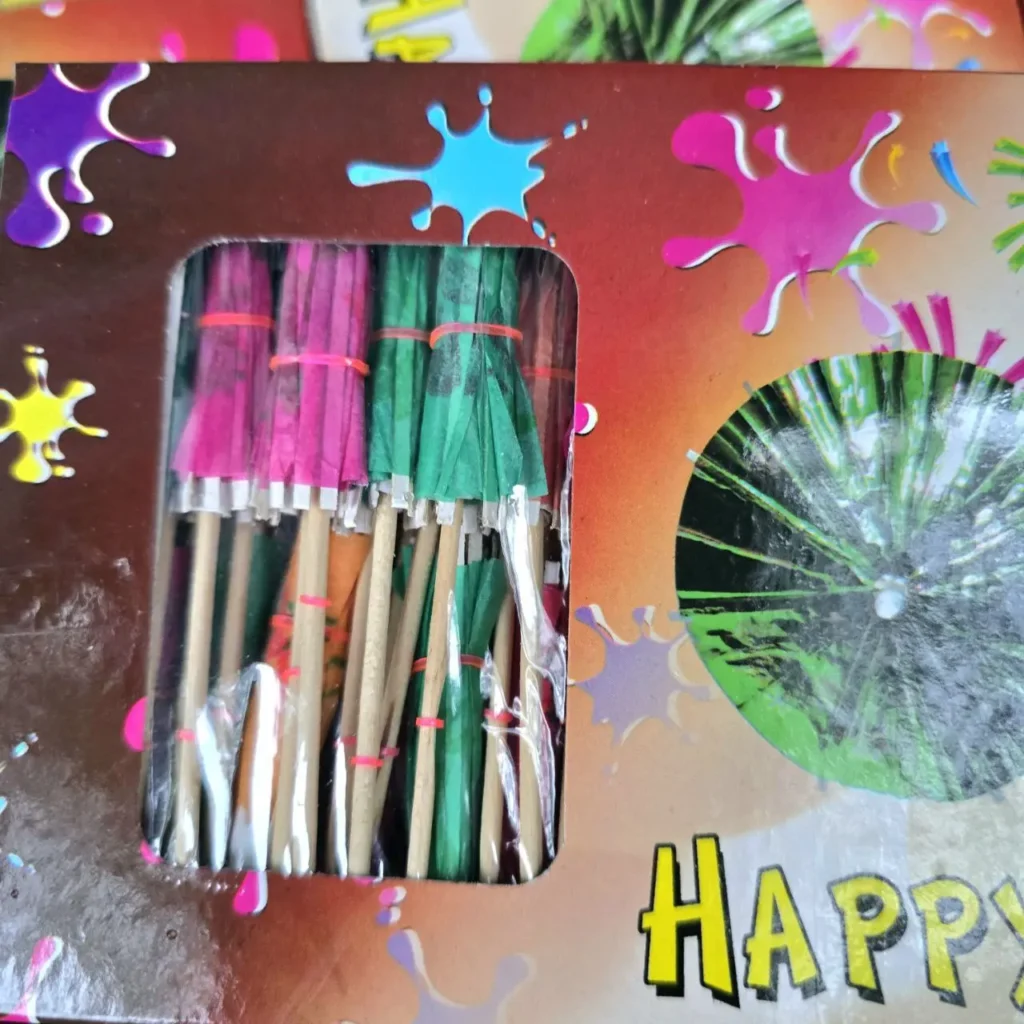 Caja festiva con sombrillas de cóctel rosas y verdes y la palabra "HAPPY". by Remates Narvaja