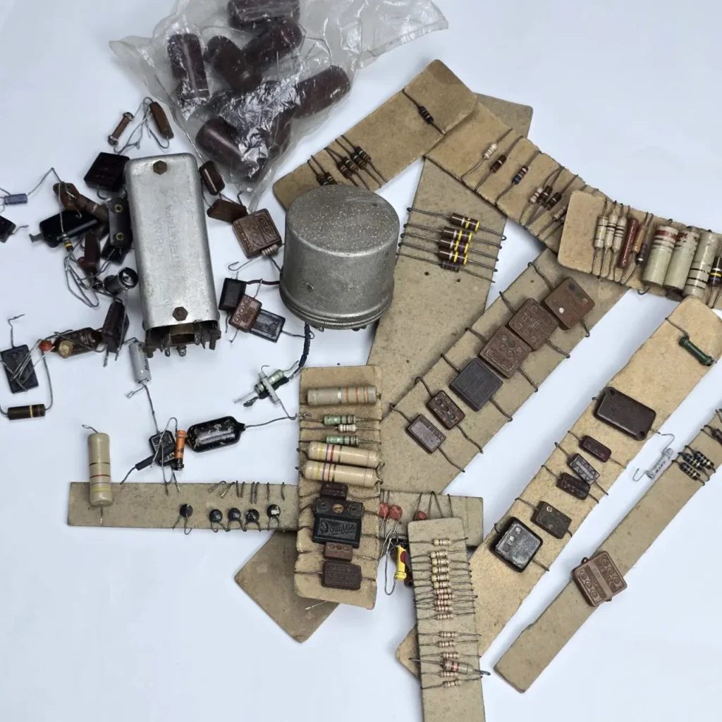 Surtido de componentes electrónicos vintage, incluyendo resistencias, condensadores y piezas de radio antiguas montadas en tiras de cartón. by Remates Narvaja