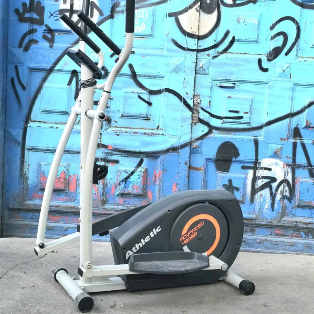 Elíptica Athletic Advanced 480EP frente a una puerta azul con grafitis. by Remates Narvaja
