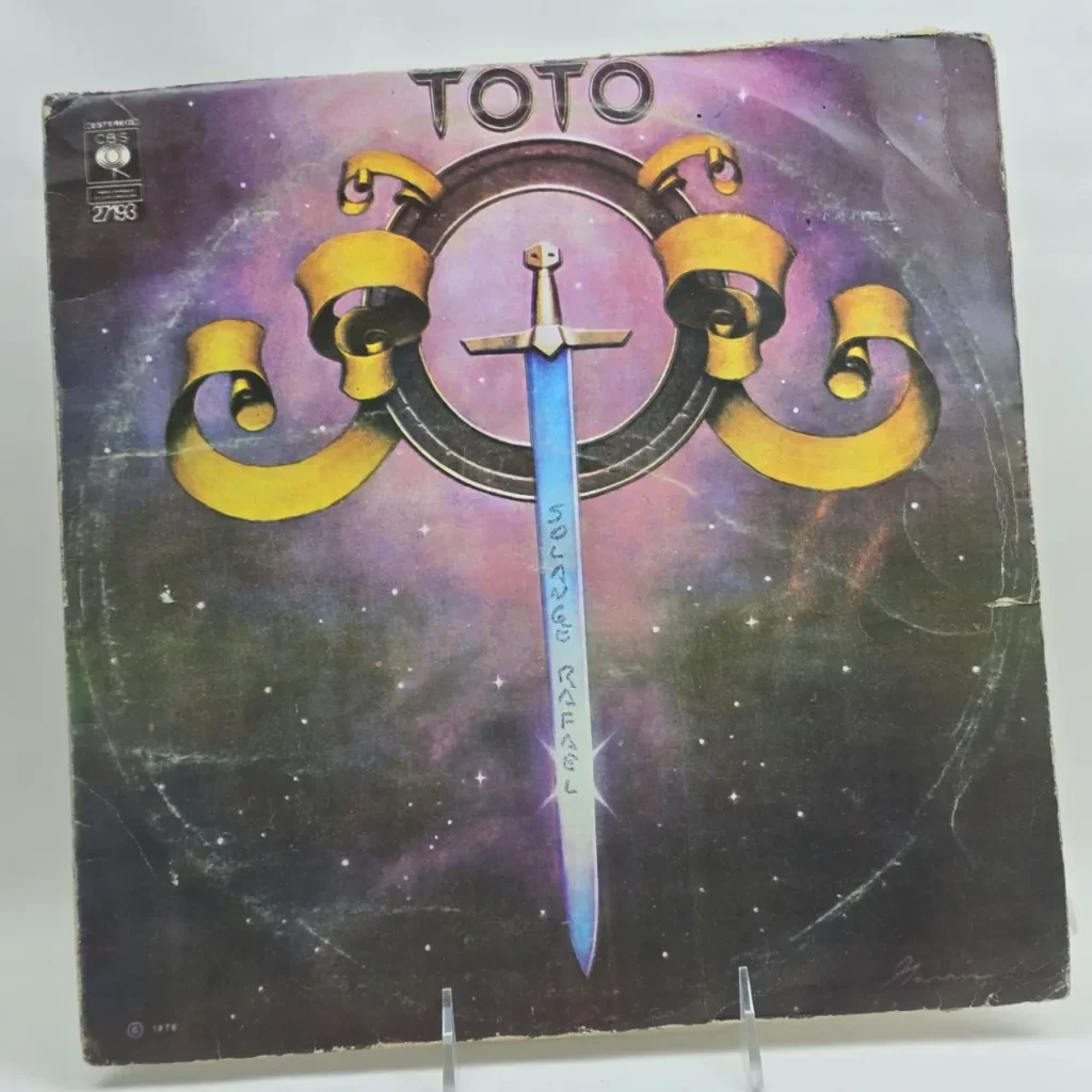 Portada del álbum debut de Toto con una espada azul y fondo cósmico. by Remates Narvaja