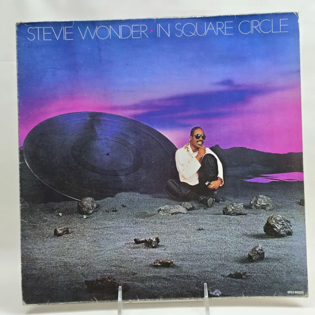Portada del álbum "In Square Circle" de Stevie Wonder con el artista sentado junto a un vinilo gigante. by Remates Narvaja