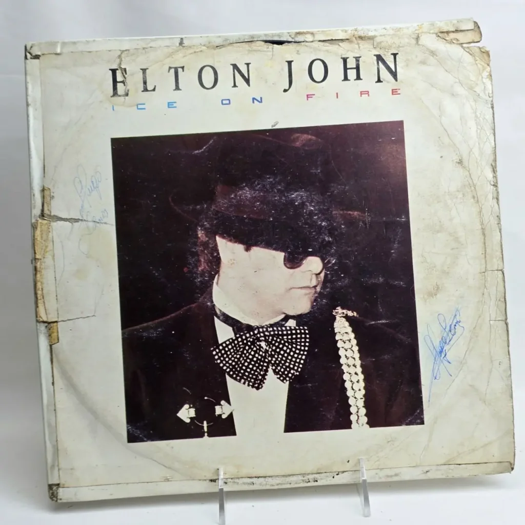 Portada del álbum de vinilo "Ice on Fire" de Elton John, con Elton John en esmoquin y gafas de sol, mostrando desgaste y autóg by Remates Narvaja