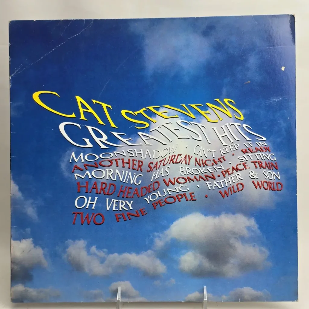 Portada del álbum Cat Stevens Greatest Hits con cielo azul y nubes, mostrando canciones como Moonshadow, Wild World, Peace Train y Father & Son. by Remates Narvaja