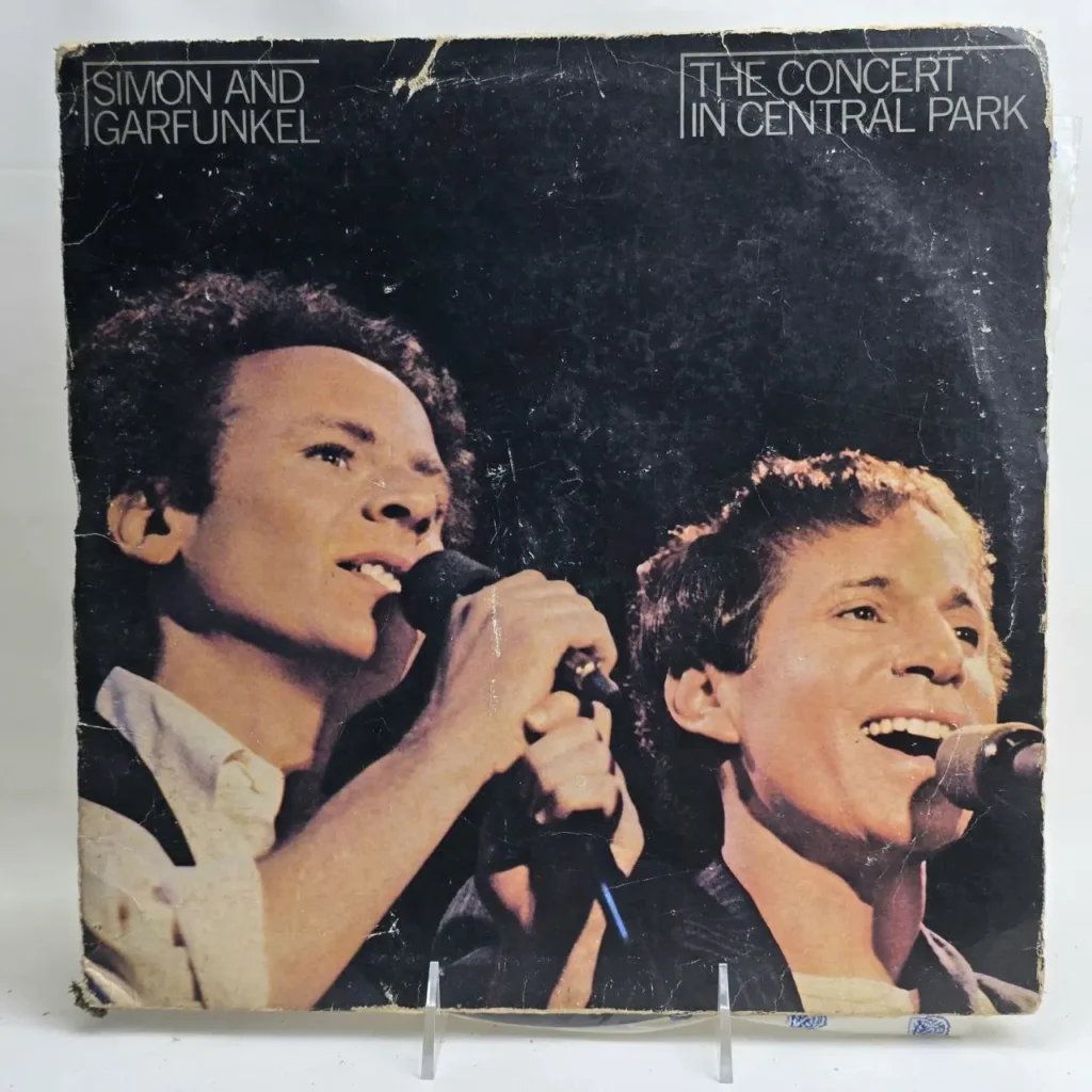 Portada del álbum de vinilo "The Concert in Central Park" de Simon & Garfunkel, mostrando a ambos cantantes con micrófonos. by Remates Narvaja