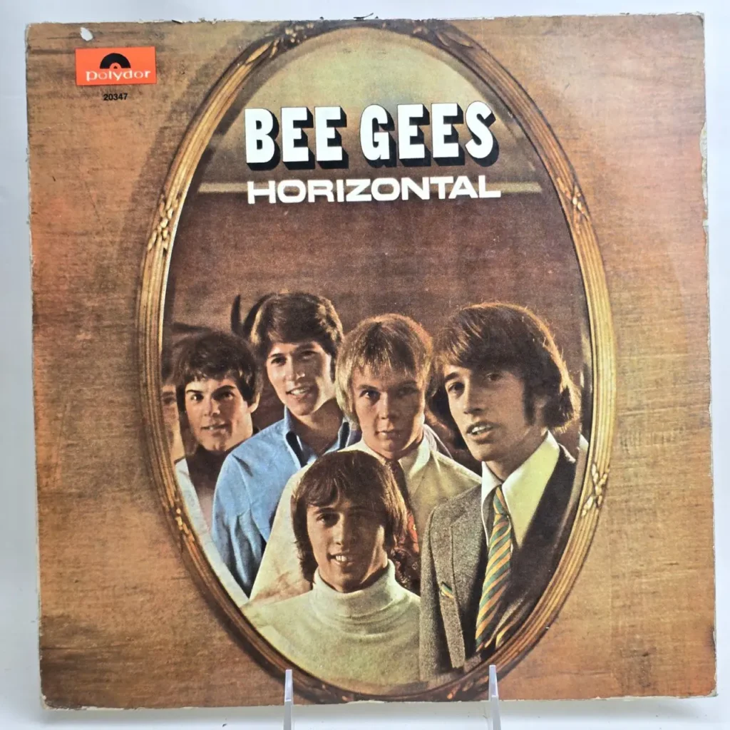 Portada del álbum "Horizontal" de Bee Gees, con cinco miembros de la banda reflejados en un espejo ovalado sobre un fondo de madera. by Remates Narvaja
