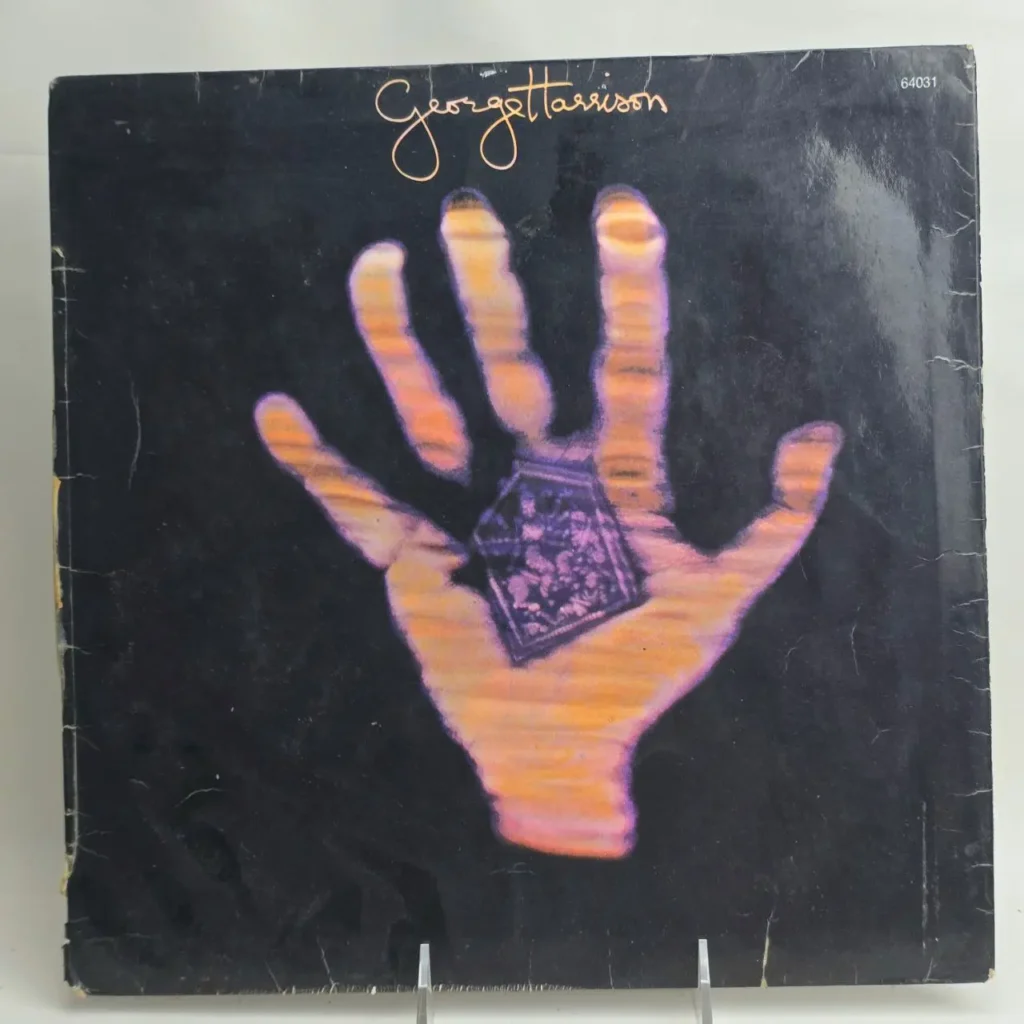 Portada del álbum George Harrison Dark Horse con una mano brillante sosteniendo un objeto cristalino. by Remates Narvaja