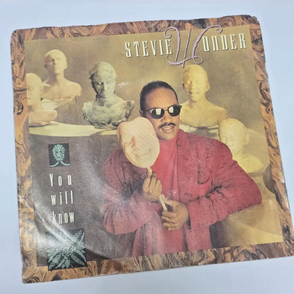 Portada del single de vinilo "You Will Know" de Stevie Wonder, con el artista en gafas de sol y una máscara. by Remates Narvaja