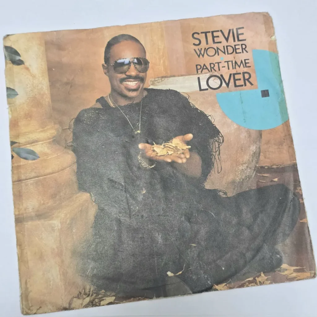 Portada del sencillo Stevie Wonder - Part-Time Lover, con Stevie Wonder sonriendo con gafas de sol y sosteniendo hojas. by Remates Narvaja