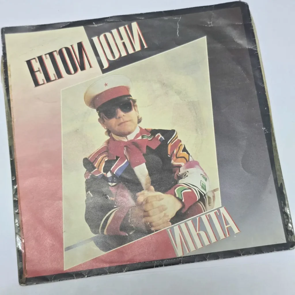 Portada del single "Nikita" de Elton John, con el artista vestido de militar y gafas de sol. by Remates Narvaja
