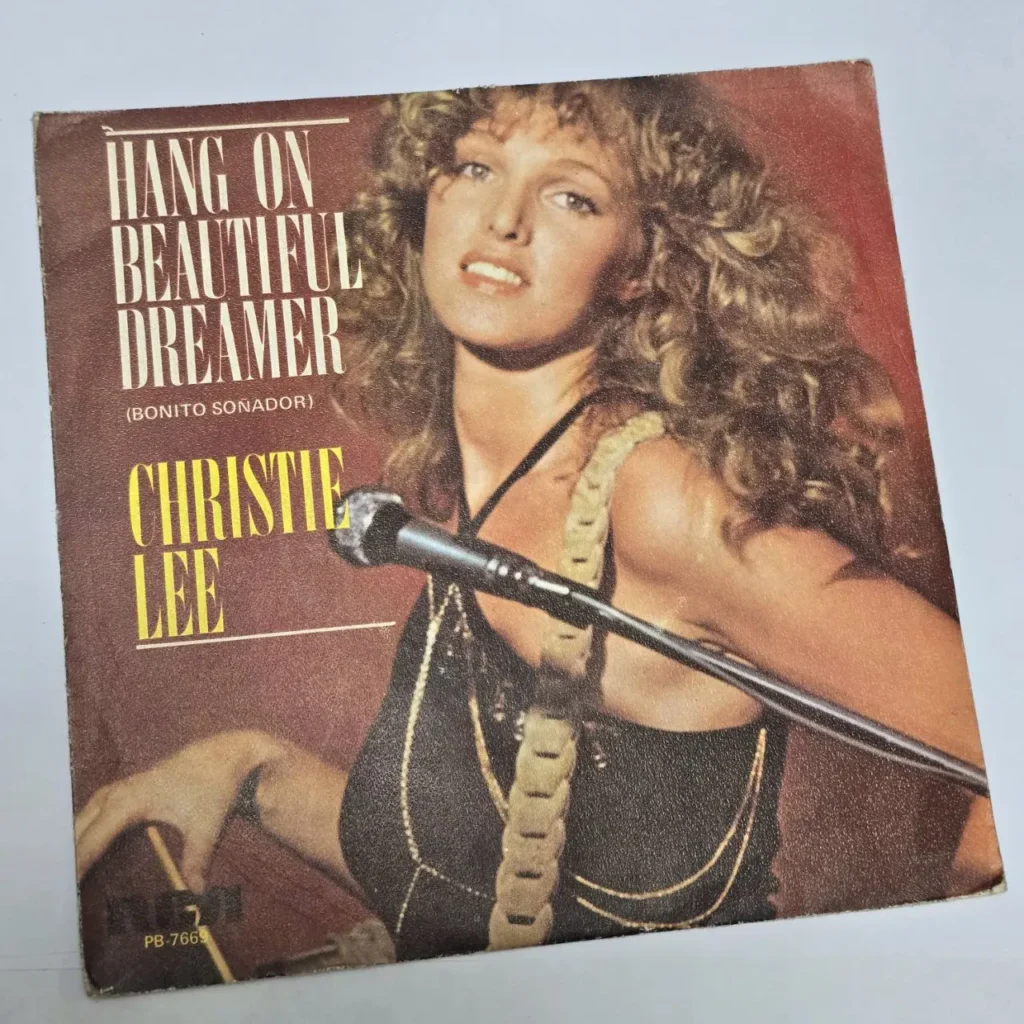 Portada de single de Christie Lee "Hang On Beautiful Dreamer", con la cantante frente a un micrófono. by Remates Narvaja