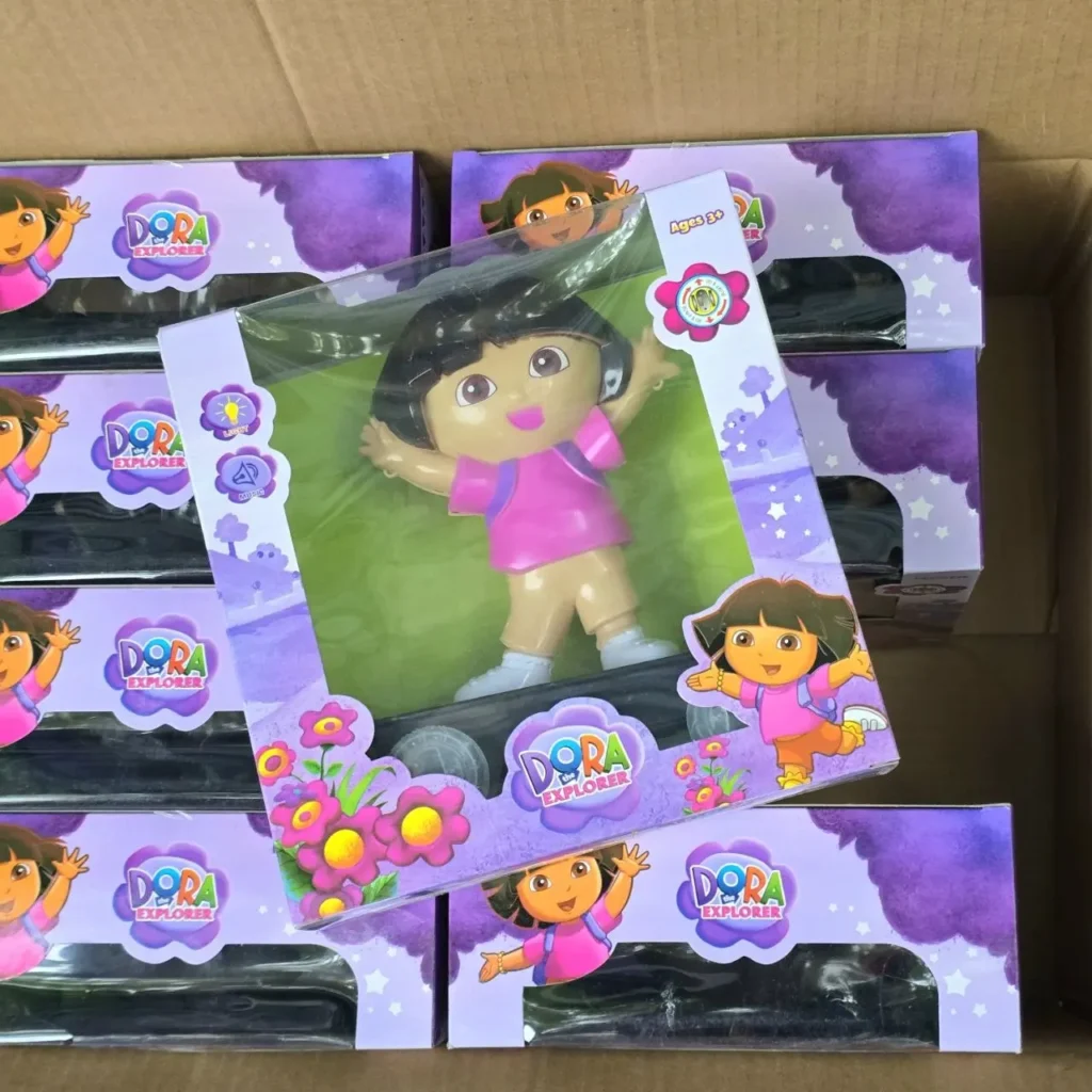 Muñeca Dora la Exploradora en caja con luz y música, rodeada de más cajas de juguetes Dora. by Remates Narvaja