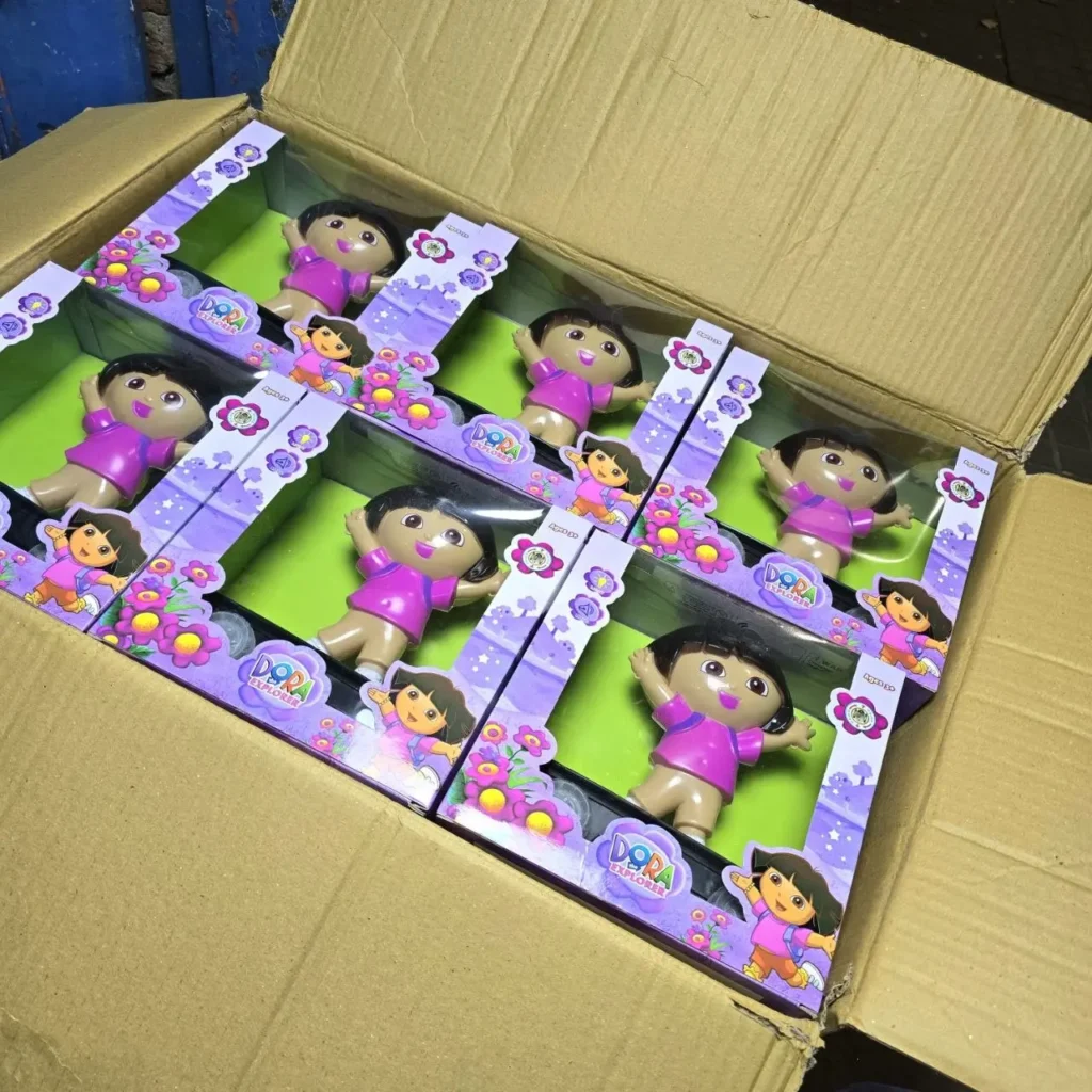 Caja de cartón con varias muñecas de Dora la Exploradora en sus empaques individuales. by Remates Narvaja