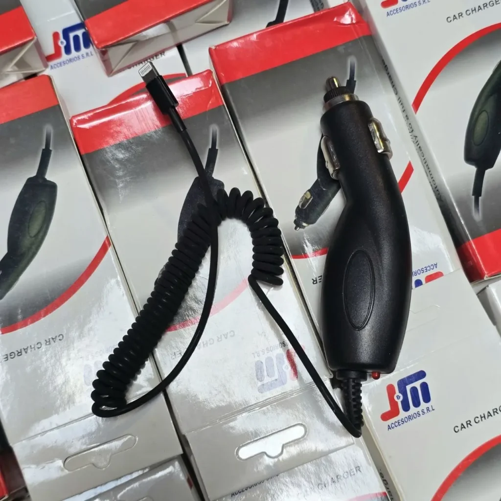 Cargador de coche negro con cable Lightning en espiral sobre cajas de producto. by Remates Narvaja