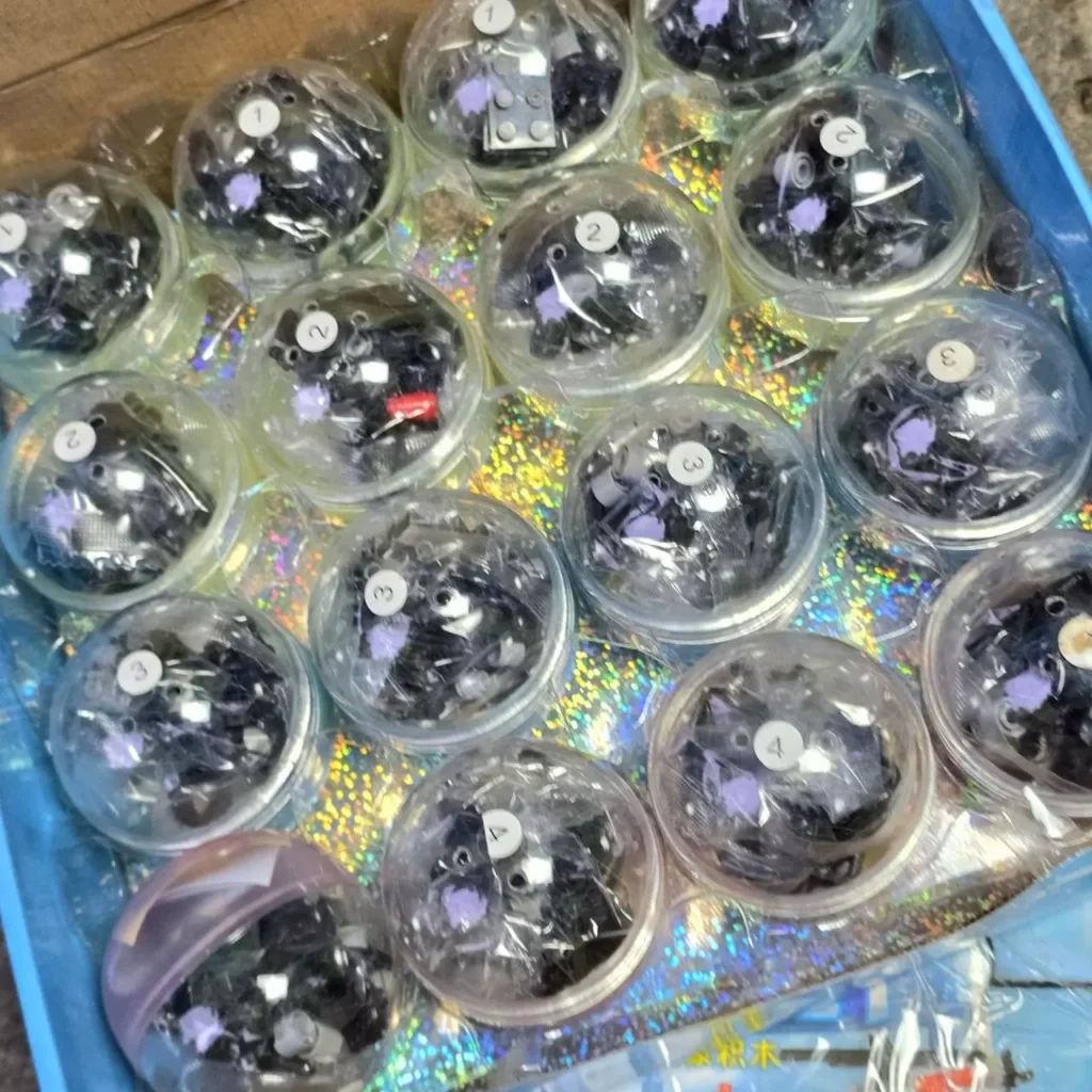 Cápsulas de gashapon con bloques de construcción negros y morados, numeradas. by Remates Narvaja