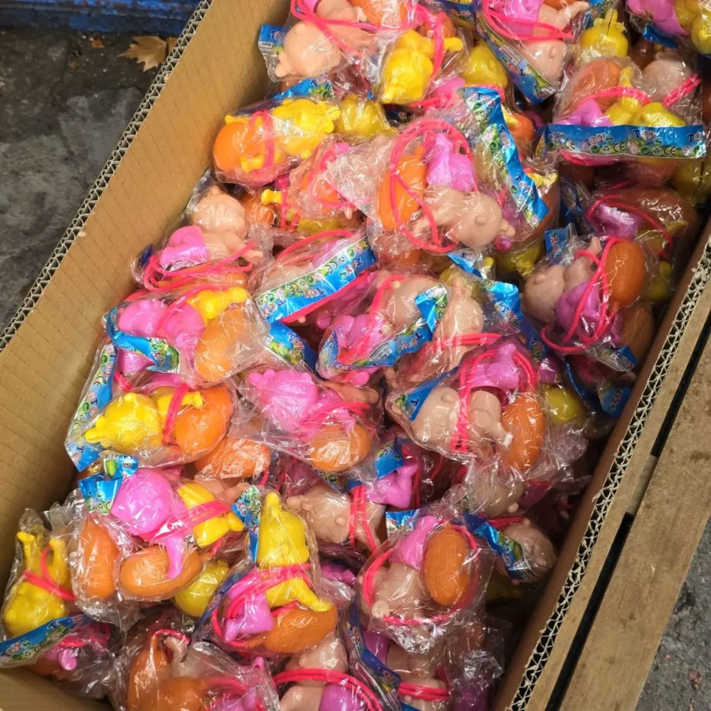 Caja llena de pequeños juguetes de muñecas bebé de plástico de colores, envueltos individualmente. by Remates Narvaja