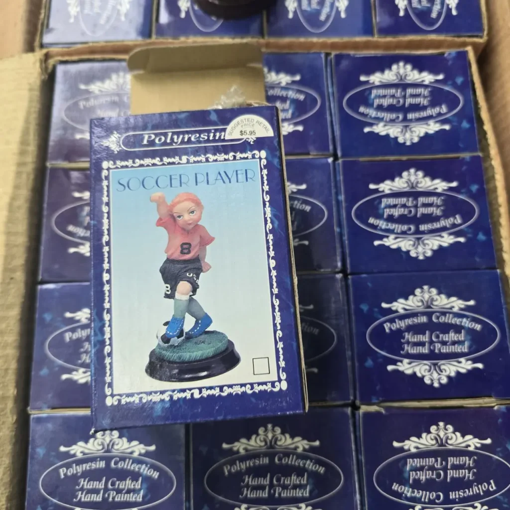 Figura de jugador de fútbol de poliresina pintada a mano en caja azul, rodeada de más cajas de la colección. by Remates Narvaja