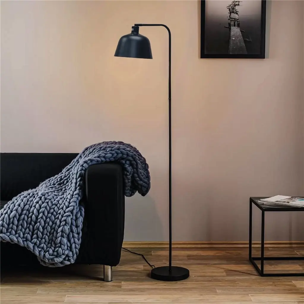 Lámpara de pie negra moderna en un salón junto a un sofá con manta tejida. by Remates Narvaja