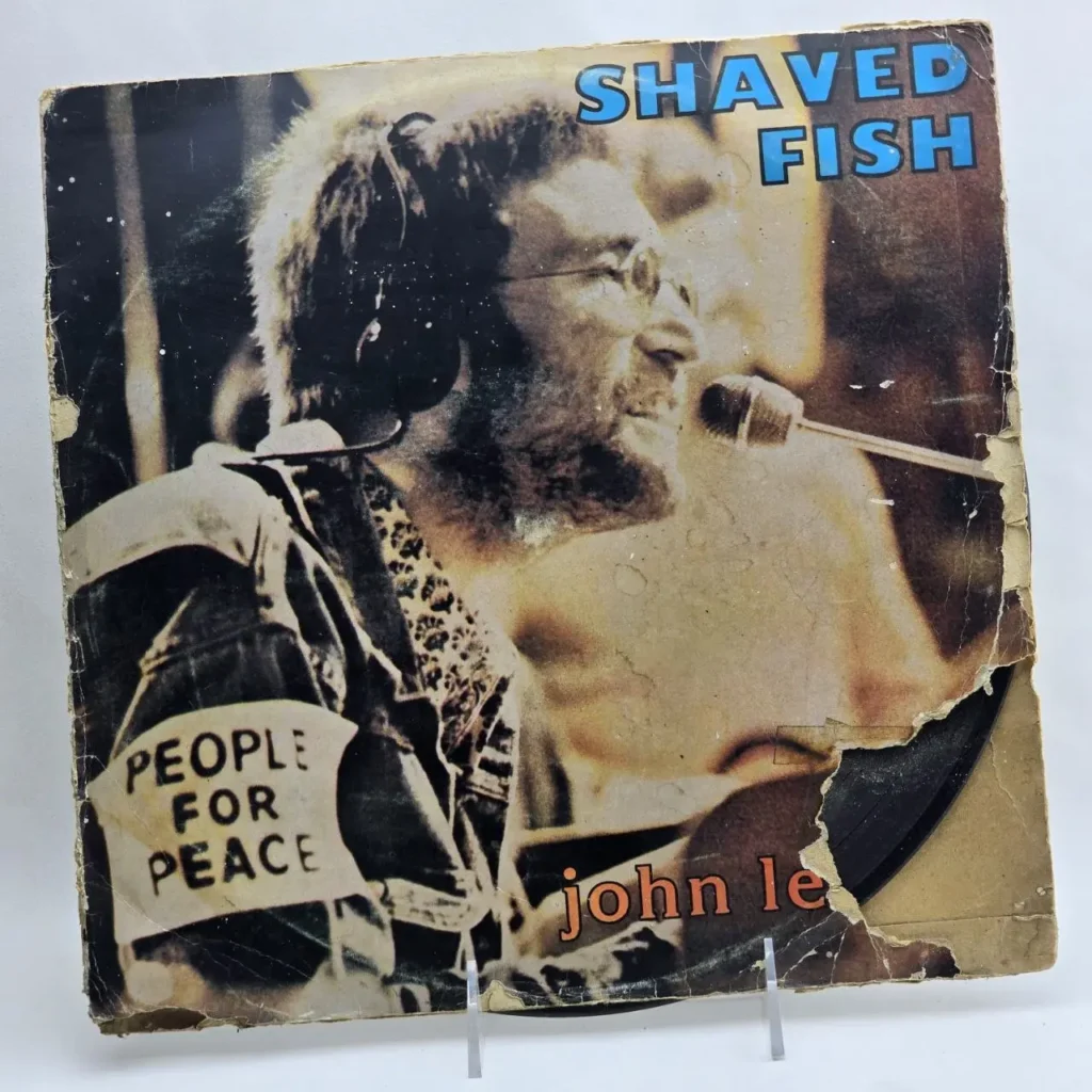Portada del álbum "Shaved Fish" de John Lennon, con él llevando un brazalete "People for Peace". La cubierta está desgastada. by Remates Narvaja