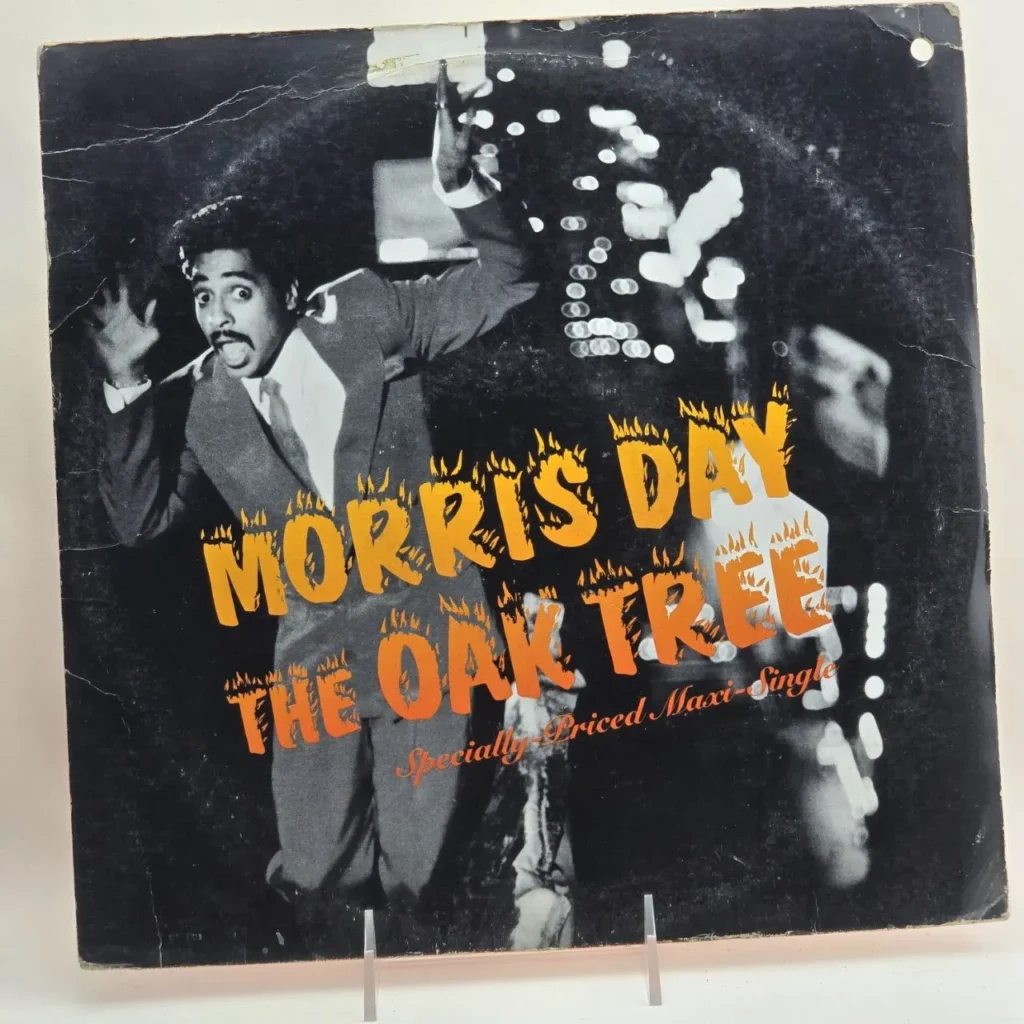 Portada del maxi-single Morris Day - The Oak Tree, con Morris Day en traje y texto naranja de fuego. by Remates Narvaja