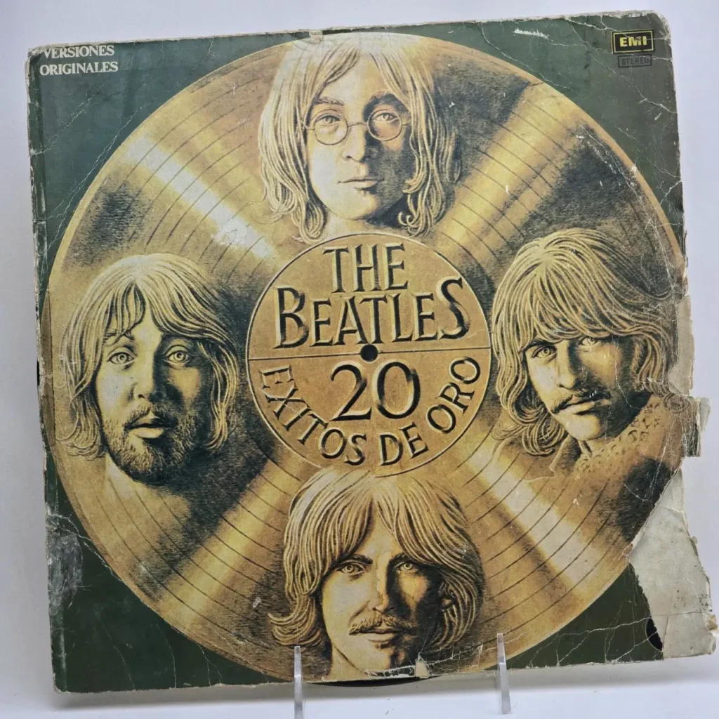 Portada de álbum vintage de The Beatles "20 Éxitos de Oro" con los rostros de los cuatro miembros alrededor de un disco dorado. by Remates Narvaja