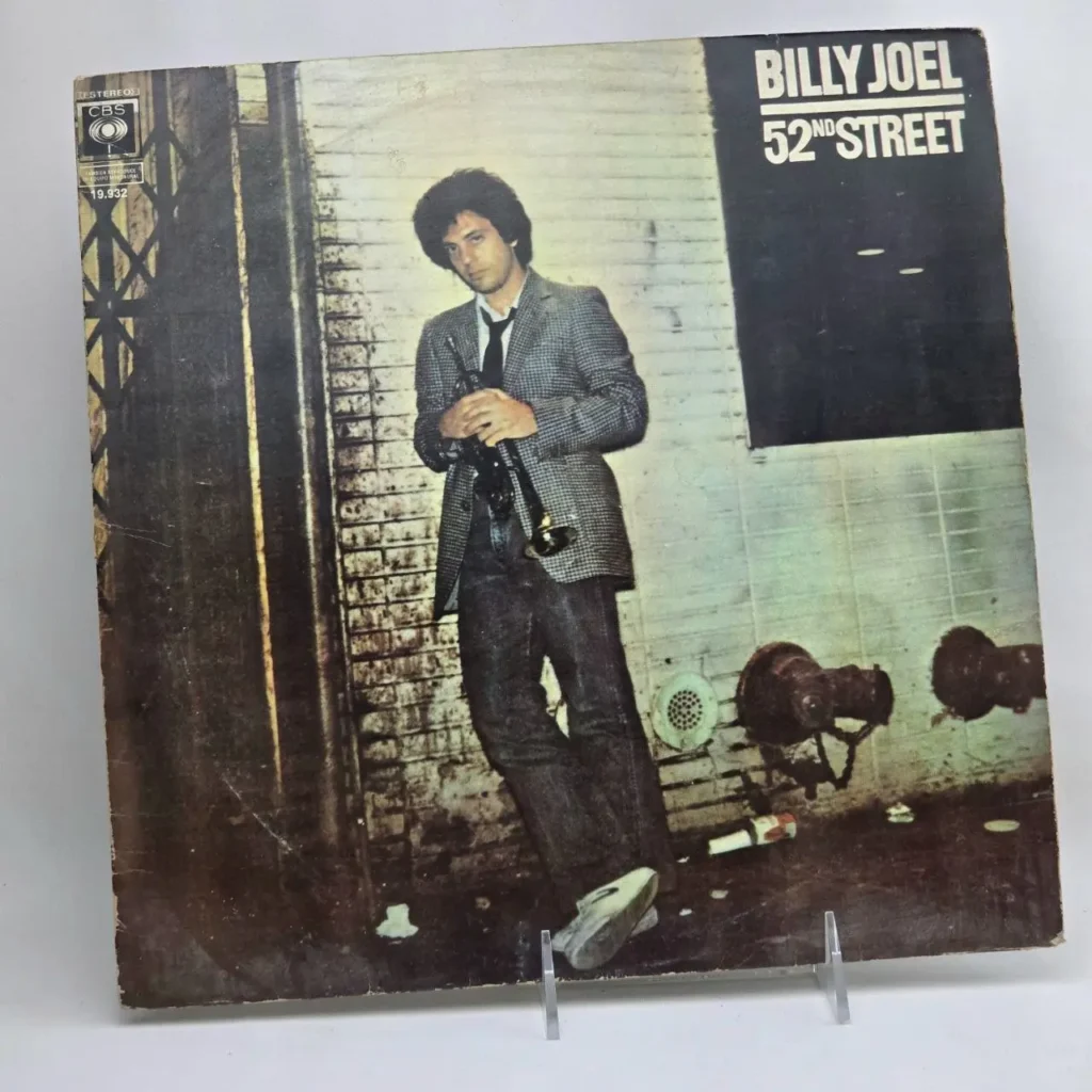 Portada del álbum de vinilo Billy Joel 52nd Street, con Billy Joel posando con una trompeta en un entorno urbano. by Remates Narvaja