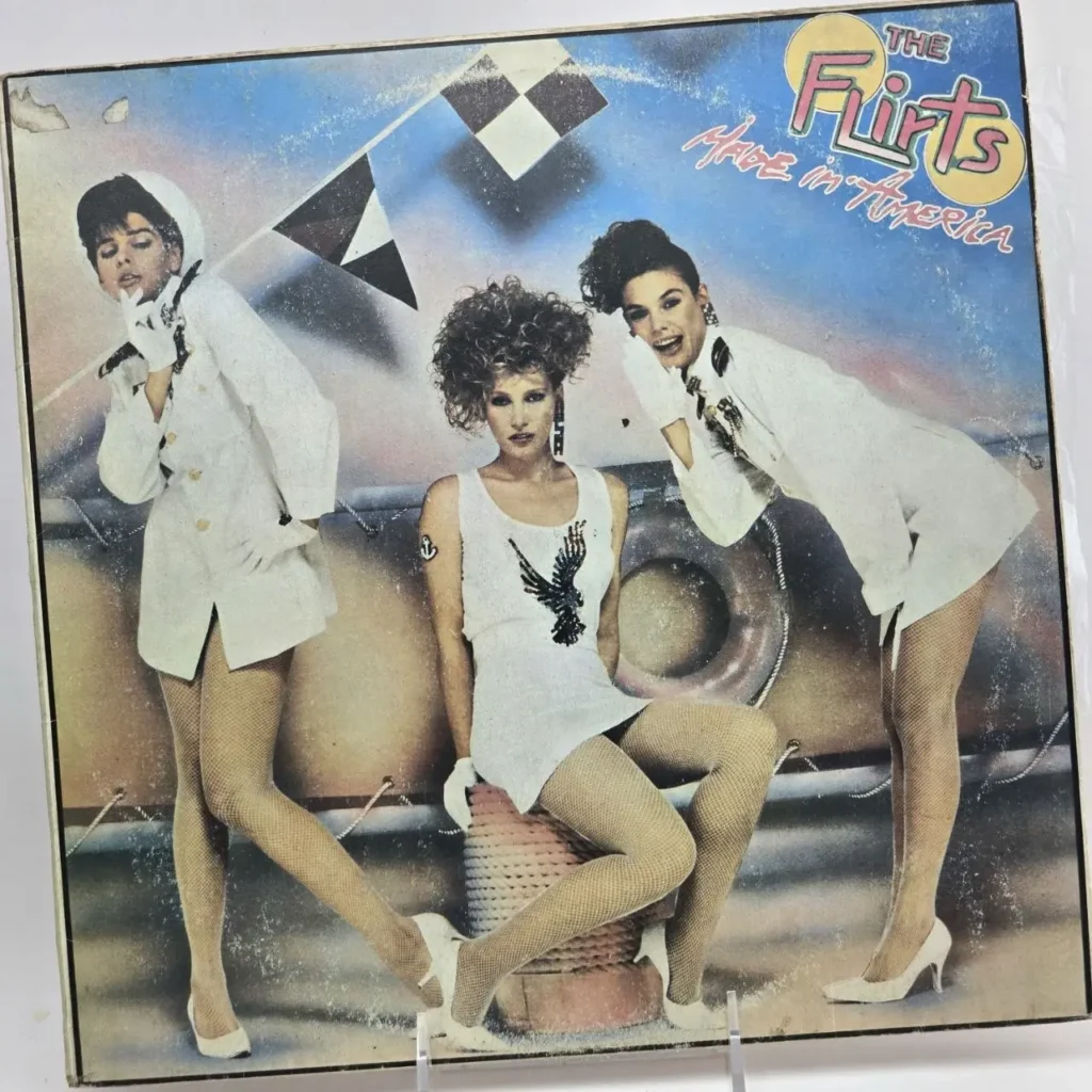 Portada del álbum "The Flirts - Made in America" con tres mujeres en atuendos blancos estilo años 80 y medias de red. by Remates Narvaja