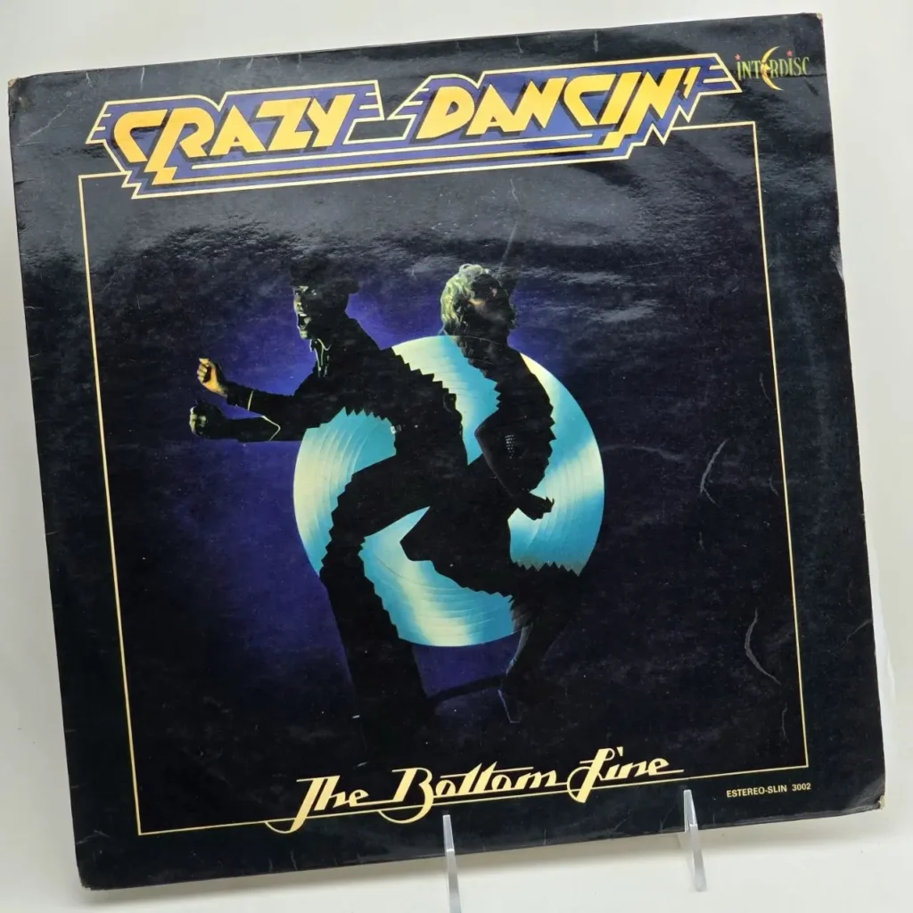Portada de álbum de vinilo "Crazy Dancin'" de The Bottom Line, con siluetas de bailarines en azul y negro. by Remates Narvaja