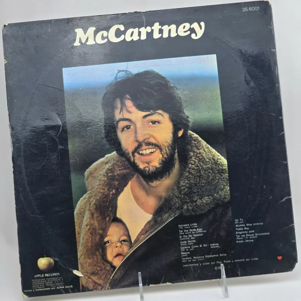 Portada del álbum "McCartney" de Paul McCartney, con él sonriendo, barbudo y un bebé asomándose de su chaqueta. S by Remates Narvaja