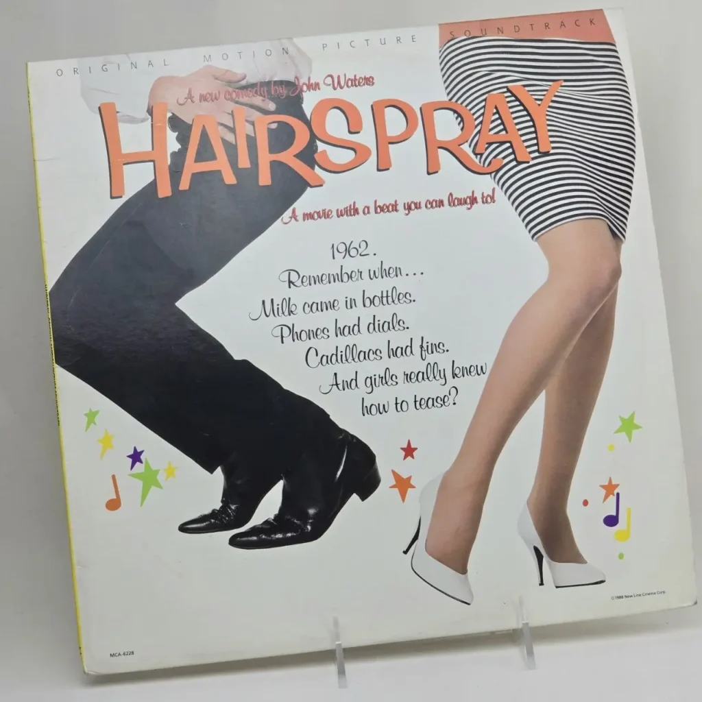 Portada del álbum Hairspray Original Motion Picture Soundtrack de John Waters, mostrando las piernas de un hombre y una mujer con texto nostálgico de by Remates Narvaja