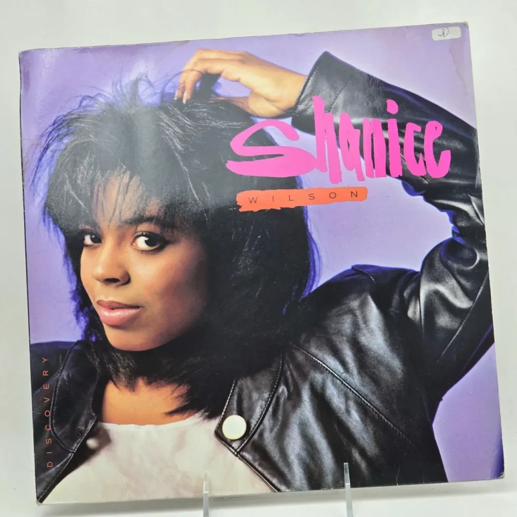 Portada del álbum 'Discovery' de Shanice Wilson, con la artista en una chaqueta de cuero negra y fondo morado. by Remates Narvaja