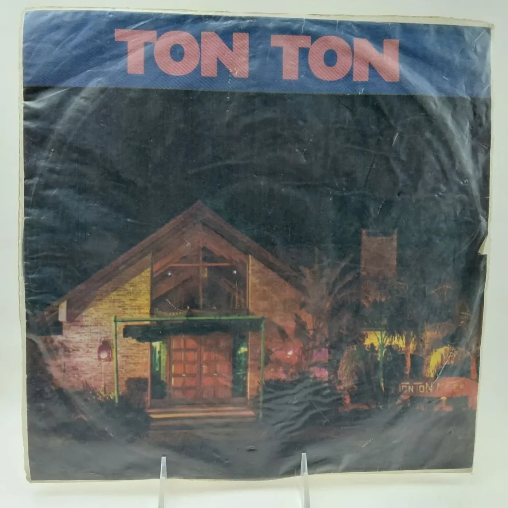 Portada de disco "TON TON" con un edificio iluminado de noche y palmeras. by Remates Narvaja