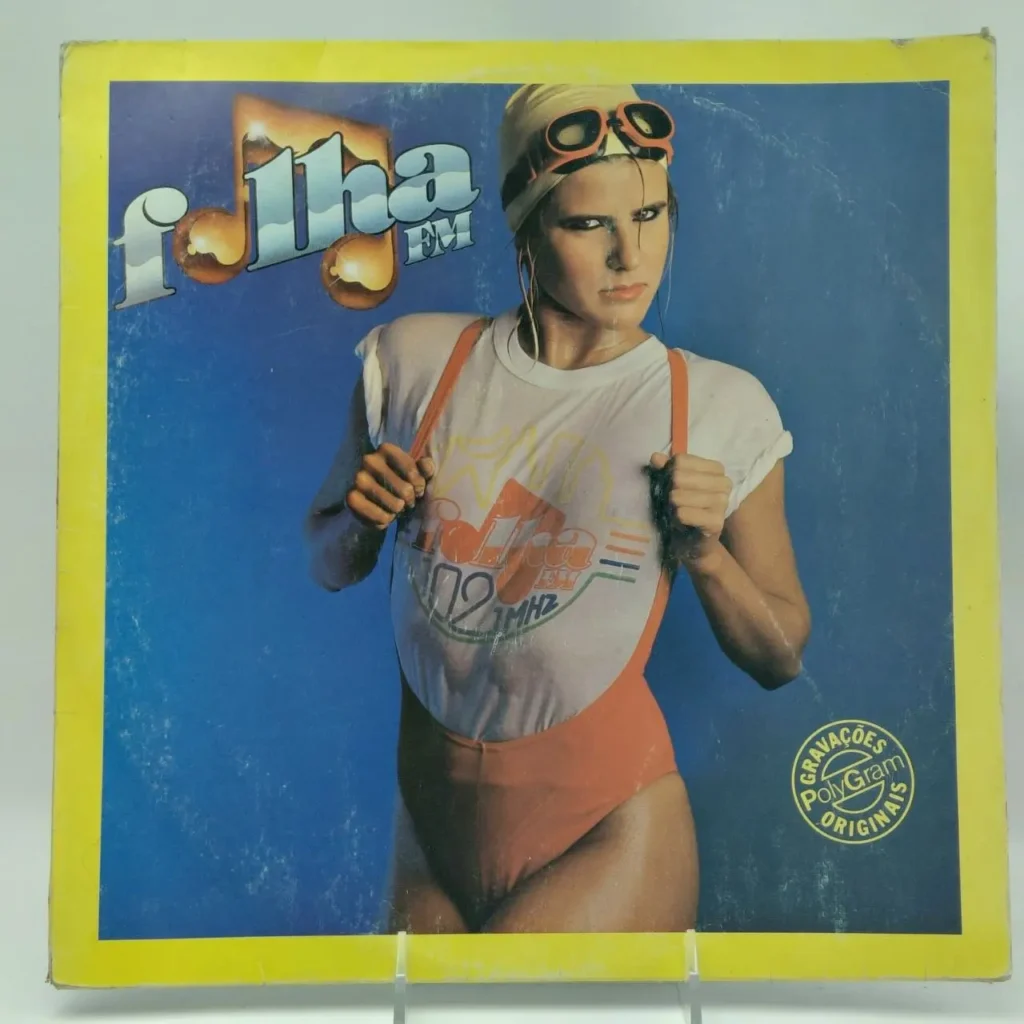Capa de álbum Folha FM 102 MHz dos anos 80 com mulher de maiô laranja, camiseta branca molhada e óculos by Remates Narvaja