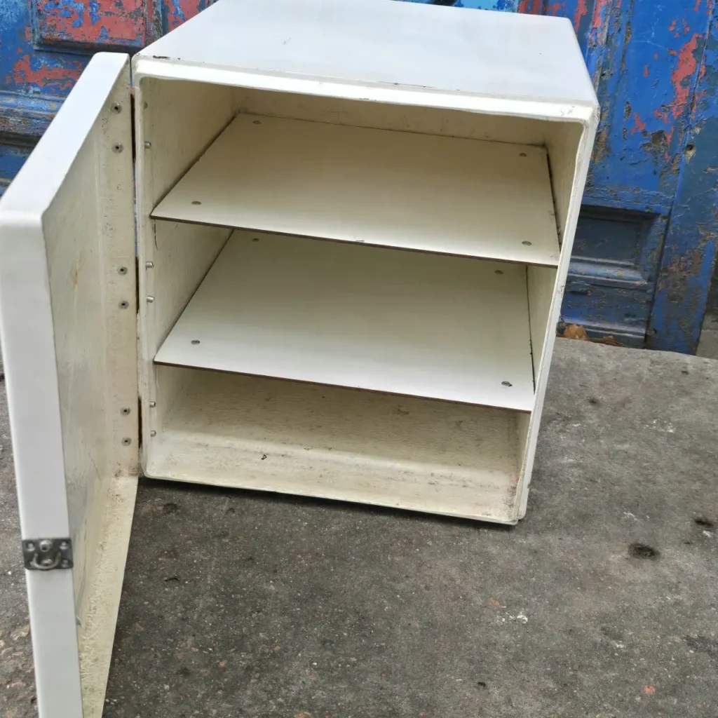 Armario blanco con puerta abierta y dos estantes, sobre suelo de hormigón. by Remates Narvaja
