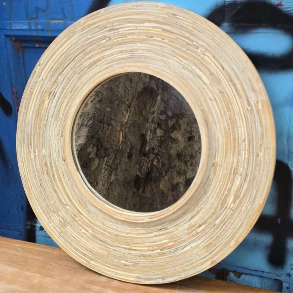 Espejo redondo decorativo con marco de madera en capas, reflejando corteza de árbol. by Remates Narvaja