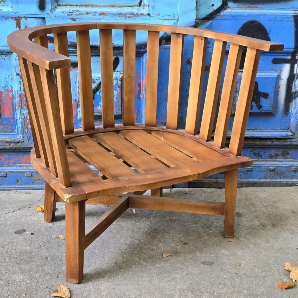 Sillón de madera rústico con respaldo curvo frente a una pared azul con graffiti. by Remates Narvaja