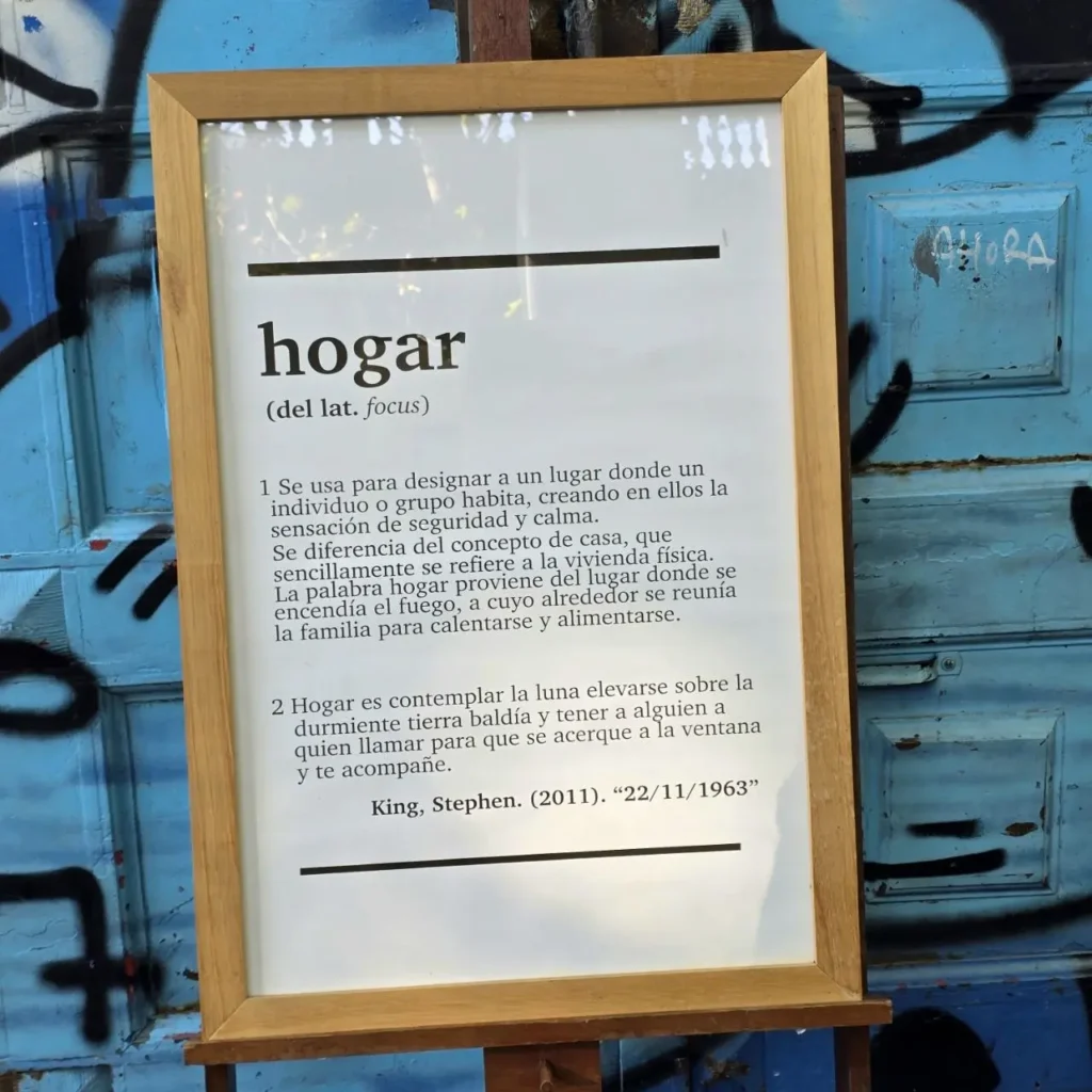 Cuadro con la definición de "hogar" y una cita de Stephen King, sobre fondo azul con grafitis. by Remates Narvaja