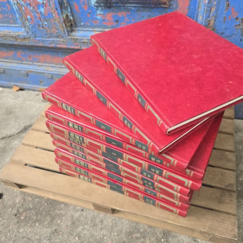 Pila de libros rojos antiguos sobre un palé de madera. by Remates Narvaja