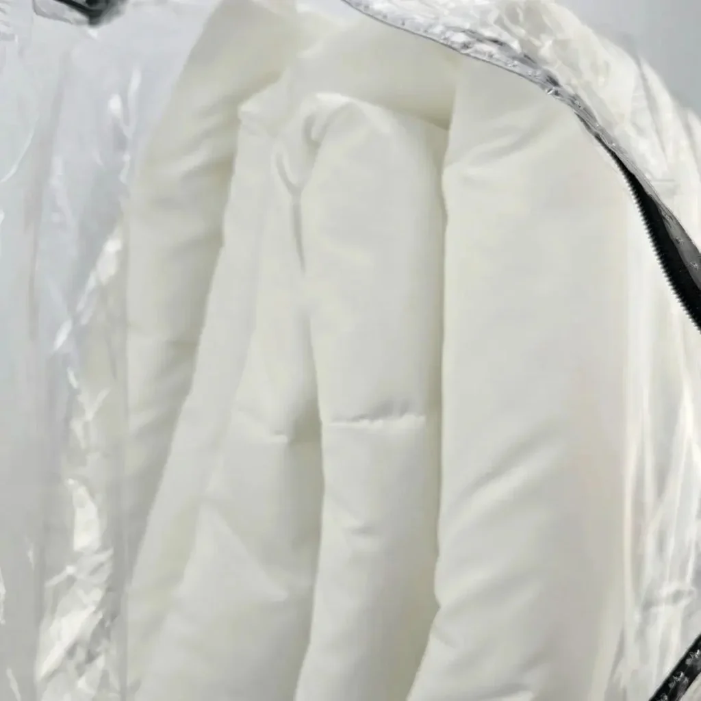 Acolchado blanco bajo material transparente brillante con cremallera. by Remates Narvaja