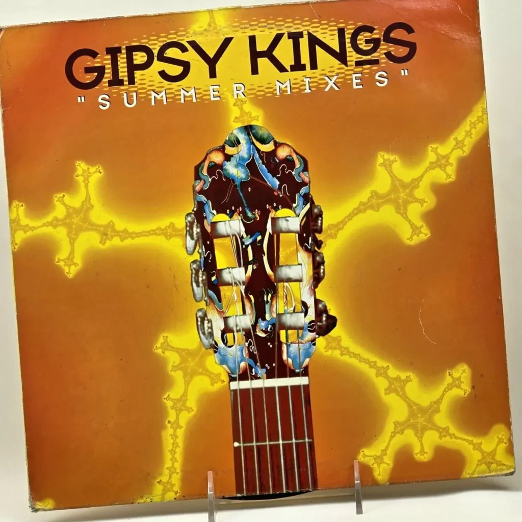 Portada del álbum Gipsy Kings "Summer Mixes" con la pala de una guitarra flamenca sobre un fondo naranja y amarillo con patrones brillantes. by Remates Narvaja