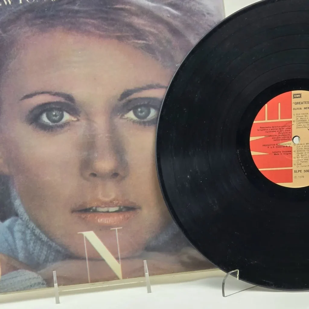 Portada de vinilo Olivia Newton-John Greatest Hits con su rostro y el disco negro. by Remates Narvaja