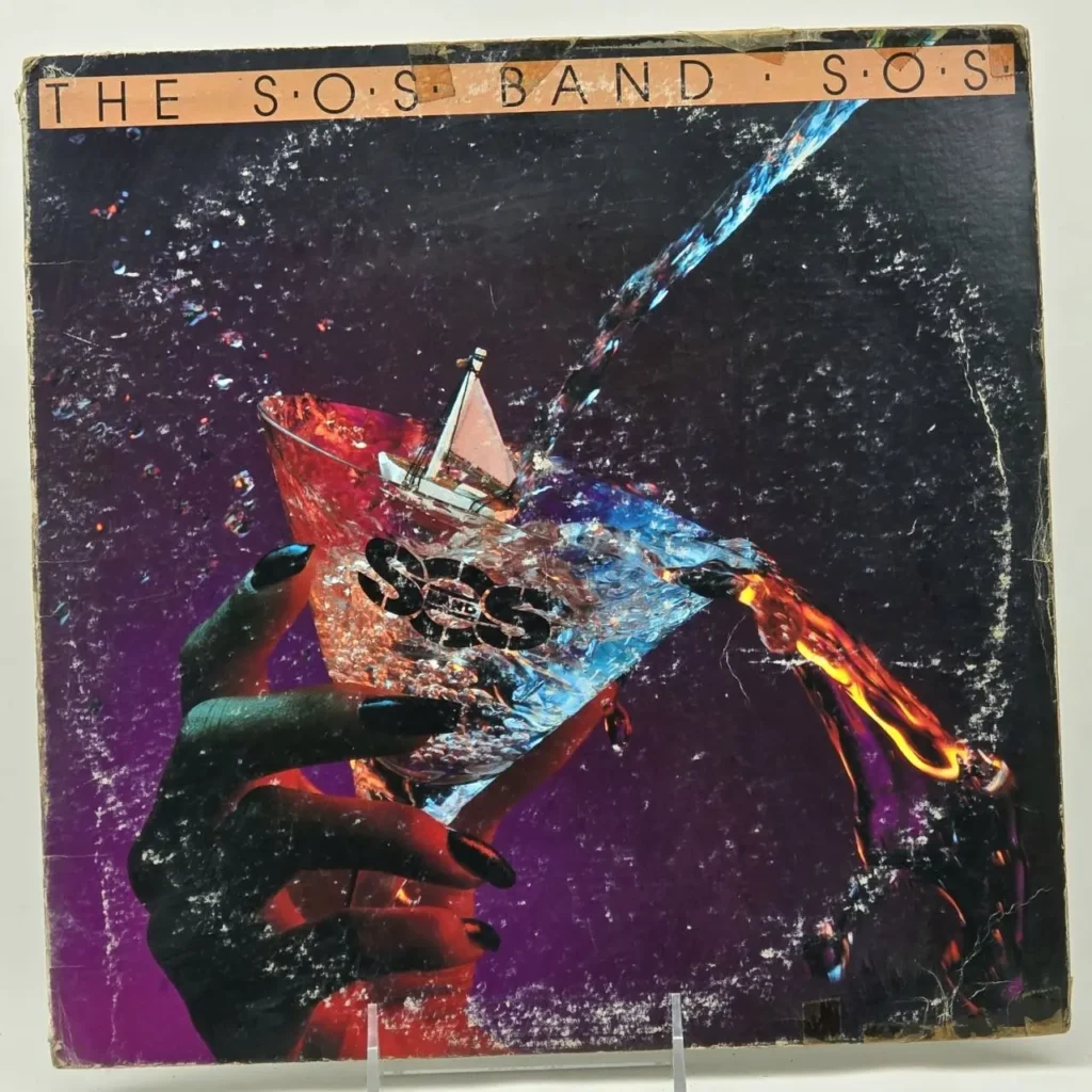 Portada del álbum de vinilo "S.O.S." de The S.O.S. Band, con una mano sosteniendo un by Remates Narvaja